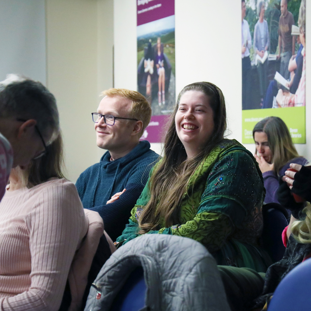 People attending a Libraries Unlimited event seated in a library space watching a film.