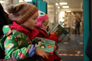 two young children collecting their choose and collect books from their local library