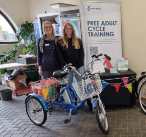 Two women stand behind a bike at a Free Adult Cycle Training Hub.